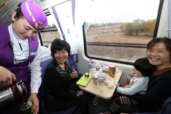 An attendant serves passengers on a train running between Urumqi and Kuerle in the Xinjiang Uygur autonomous region. (Photo by Li Xiongxin/For China Daily)