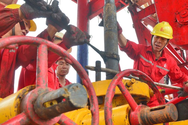Workers inspect an oil well at a subsidiary of Sinopec Group in Puyang, Henan province. (Photo by Tong Jiang/For China Daily)