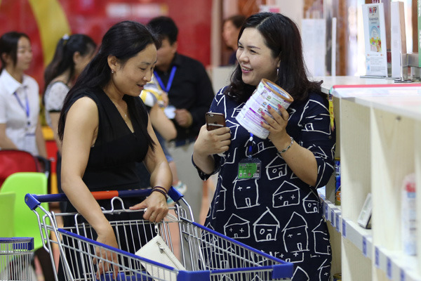 A saleswoman promotes imported milk powder at an imported goods fair in Kunming, Yunnan province. (Photo by Yang Zheng/For China Daily)