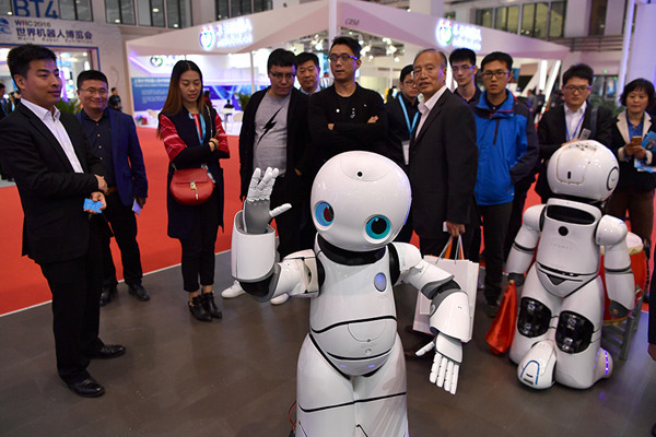 Visitors watch robots for business uses during the 2016 World Robot Conference in Beijing, Oct 20, 2016. (Photo/Xinhua)