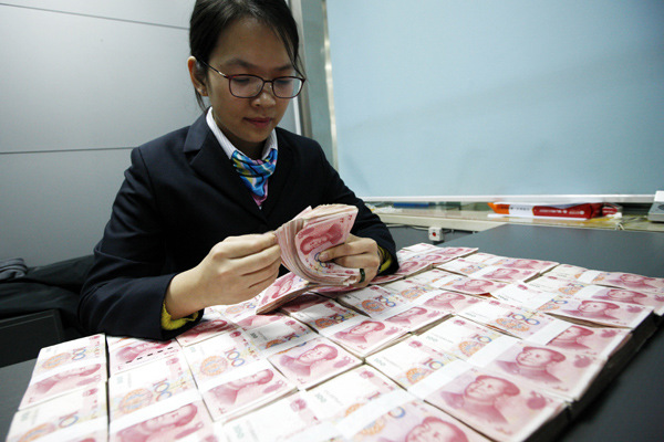 A worker at the Industrial and Commercial Bank of China counts banknotes at a branch in Huaibei, Anhui province, on Dec 1, 2015. (Photo by Xie Zhengyi/For China Daily)
