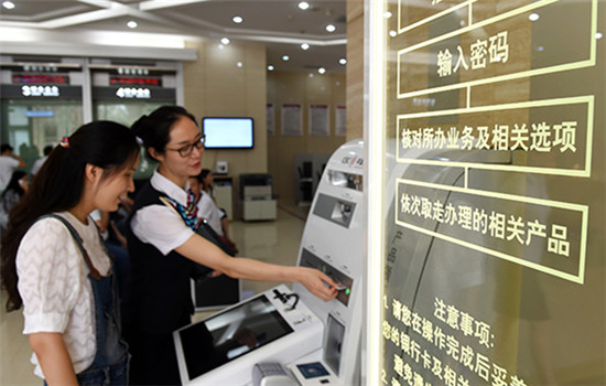 A bank clerk tells a customer how to seek helps with service machines at an outlet of the Industrial and Commercial Bank of China in Zhengzhou, capital of Henan province. (Photo provided to China Daily)