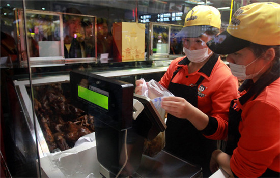 Two employees weigh products at a Zhouheiya store at a railway station in Wuchang, Hubei province. (CHINA NEWS SERVICE)