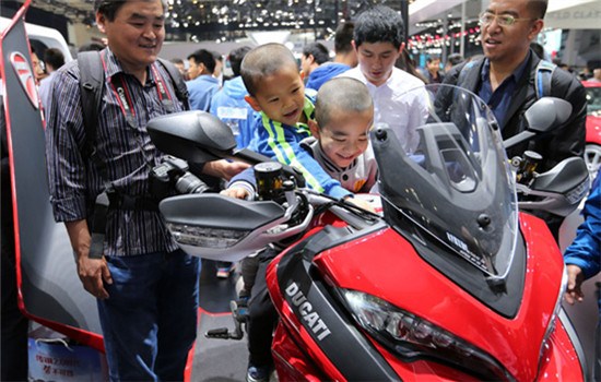 Two boys sit on a motorcycle at an auto expo in Beijing. (Wang Zhuangfei / For China Daily)