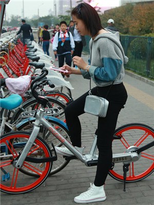 A user scans the QR code with her smartphone for a Mobike ride in Beijing. The bike-sharing business is gaining popularity and developing fast in major cities like Beijing and Shanghai. (Zou Hong / China Daily)
