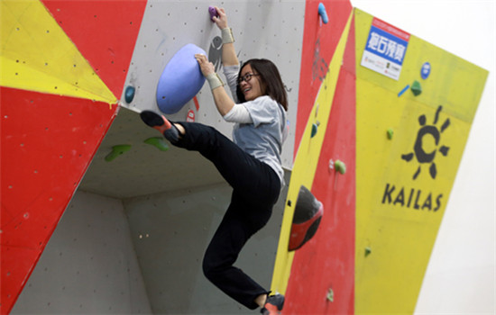 A woman tries climbing at a sports equipment exhibition in Beijing. (ZOU HONG/CHINA DAILY)
