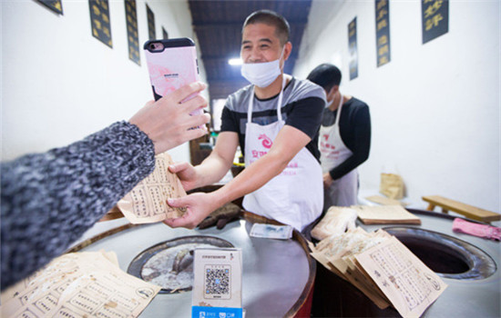 A tourist buys food via Alipay, the mobile payment service of Ant Financial Services Group, in Wuzhen, Zhejiang province.( XU KANGPING / FOR CHINA DAILY)