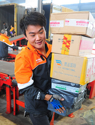 A courier carries packages at a sorting facility of STO Express Ltd in Fuyang, Anhui province, during the Nov 11 shopping festival last year. (Photo/China Daily)