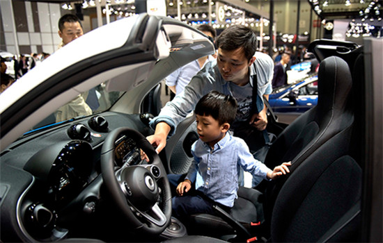 A visitor and his child try out a new car at an auto show in Wuhan, Hubei province, on Oct 12,2016. (Photo/Xinhua)