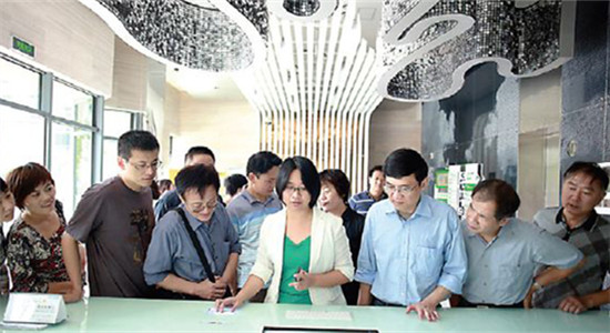 A worker with the Yangpu Cloud Computing Innovation Base in Shanghai briefs visitors on the companies operating in the Shanghai Cloud Computing Tower. (Photo/China Daily)