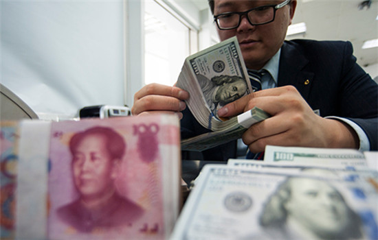 An employee at a bank counter in Nantong, Jiangsu province, counts renminbi and dollars. (Photo/China Daily)