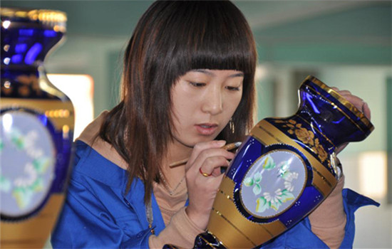 An artisan gives final touches to a vase at Honghai Glassware Co Ltd in Qixian, Shanxi province, which makes high-end products (FAN HEPING / FOR CHINA DAILY)