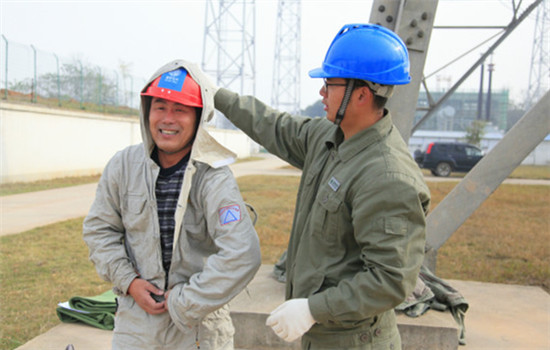 Yan Yu, son of Yan Xudong, assists him in taking off the screen clothes after he completed his work on UHV electricity cables at a UHV AC Test Base of SGCC in Wuhan, capital of Central China's Hubei province, on November 30, 2016. (Photo by Zhu Lingqing/chinadaily.com.cn)