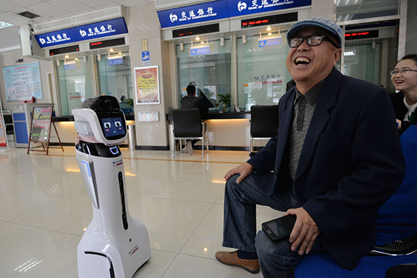 A robot interacts with a customer at a Bank of Communications branch in Handan, Hebei province. (Photo/China Daily)