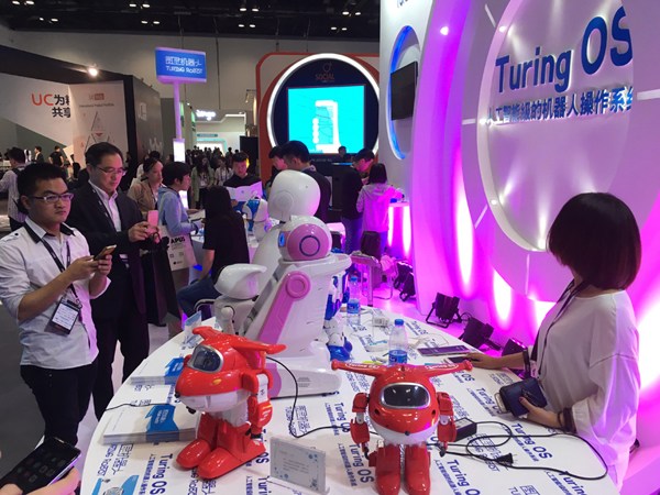 Visitors look at robots that are equipped with the Turing operation system at this year's GMIC Beijing on April 28. (Liu Zheng/chinadaily.com.cn)