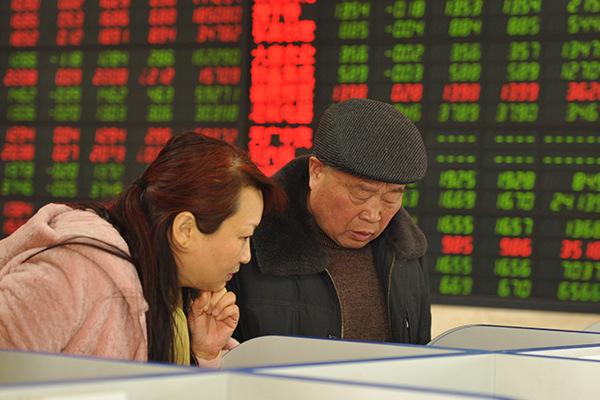 Two anxious investors check stock quotes at a brokerage in Fuyang, Anhui province, on Dec 5, 2016. (Photo/China Daily)