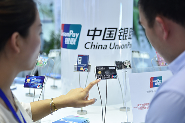 A UnionPay employee introduces new bank card services to a visitor at a show in Beijing. (Photo/Xinhua)