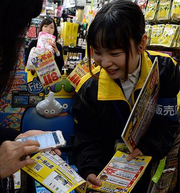 A supermarket employee explains what categories of products will get a discount, if paid through Alipay, in Tokyo, before the Double 12 (Dec 12) shopping spree. (Photo/Xinhua)