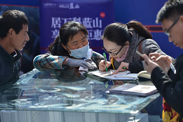 Visitors seek information at a China Vanke booth at a property fair in Shenyang, Liaoning province. (Photo/China Daily)
