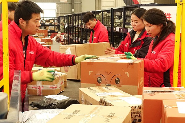 Workers sort packages after an online shopping spree in November in Fuyang, Anhui province. (Photo/China Daily)