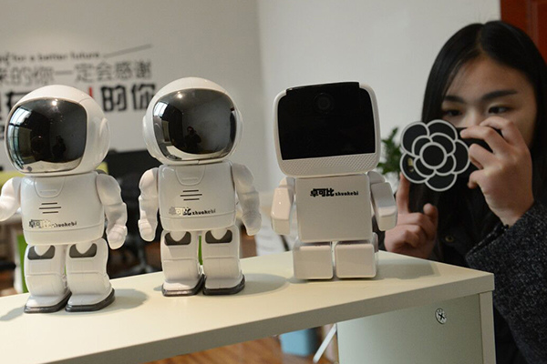 A visitor is attracted by the caretaker robots presented by a Chinese technology company in Zhengzhou, Henan province. (Photo/China Daily)