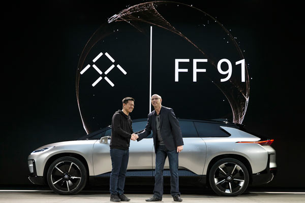 Jia Yueting (left), founder and CEO of LeEco, shakes hands with Nick Sampson, vice-president of Faraday Future, at the launch ceremony of the FF 91, an internet-enabled electric car, in Las Vegas, on Jan 3, 2017. (Photo provided to China Daily)
