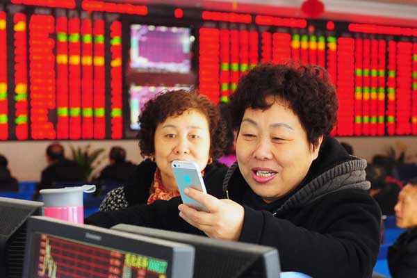 Investors read stock information at a brokerage in Fuyang, Anhui province, on Jan 3. (Photo by Wang Biao/For China Daily)