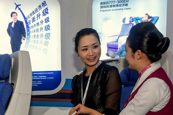 An employee (right) of China Southern Airlines introduces the airline's services to a visitor at an industry expo in Zhuhai, Guangdong province. (Photo/Xinhua