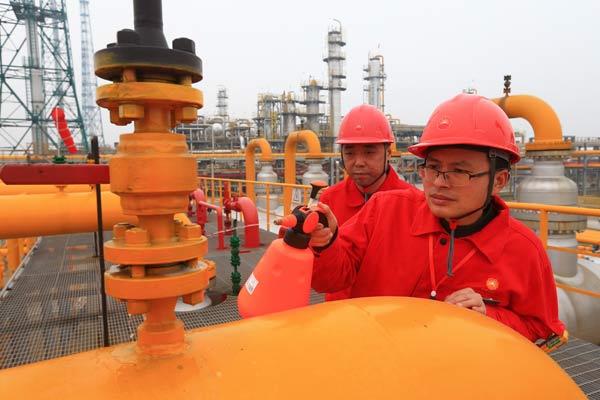 Workers from China National Petroleum Corp do cleaning work at a natural gas treatment facility in Suining, Sichuan province. (Photo by Zhong Min/For China Daily)