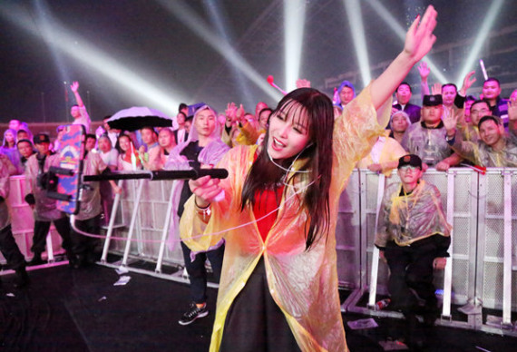 University student Nan Xun stands in the rain to broadcast a wrestling event in Henan province using her mobile phone in October. (Photo: For China Daily/Zi Jun)
