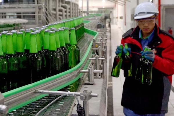 A supervisor picks some bottles of beer for quality tests at Tsingtao's production base in Luoyang, Henan province. (Photo provided to China Daily)