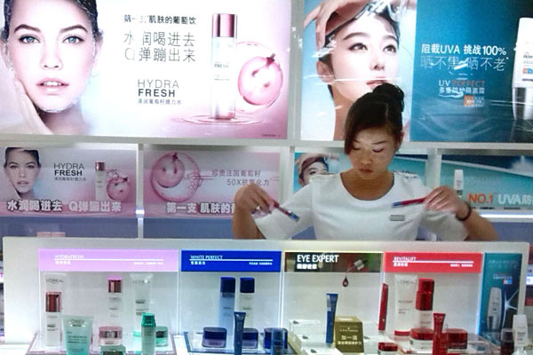 A salesgirl arranges products at a L'Oreal store at a shopping mall in Nanjing, Jiangsu. (Photo by An Xin/For China Daily)