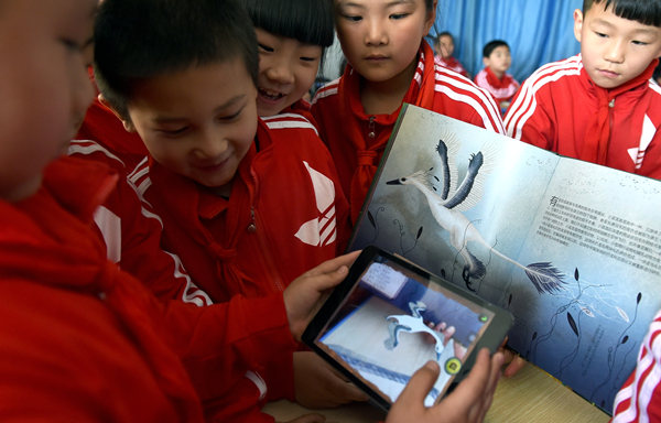 Students in a primary school in Hefei, capital of Anhui province, compare an e-book to a prited one in April. Young readers are expected to drive the growth of e-readers. GUO CHEN/ XINHUA