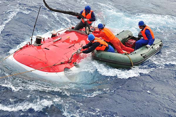 Workers try to put cables onto Jiaolong, China's first manned deep-sea submersible, after the completion of a research program.(Photo/Xinhua)