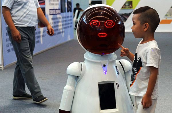 A boy interacts with a robot at a fair in Tianjin. (Photo/China Daily)
