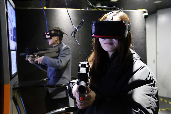Young Chinese play a first-person shooter game at a virtual reality experience center in Beijing. (Photo by Wang Zhuangfei/China Daily)