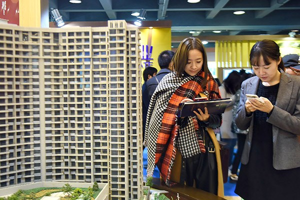Prospective home buyers check out new property prices at a sales event in Hangzhou, Zhejiang province, East China, on Dec. 17, 2016. (Photo/China Daily)
