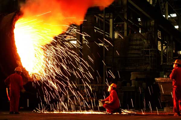 Workers clean a molten steel holder at Dalian Special Steel Co Ltd in Dalian, Liaoning province. (Photo/China Daily)
