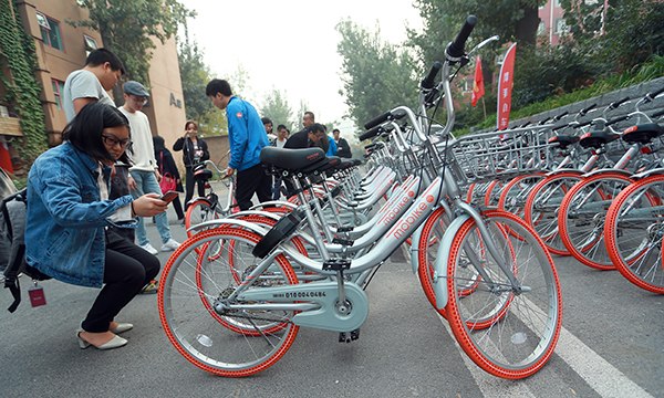 A reporter uses her cellphone to scan the QR code on a mobike on October 19, 2016 in Beijing. (Photo/China Daily)
