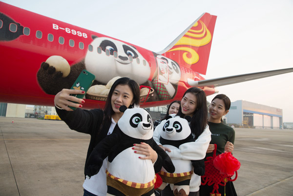 Passengers take selfies in front of a Hainan Airlines' plane after a panda-themed flight from Haikou to Beijing in late January. (Photo provided to China Daily)