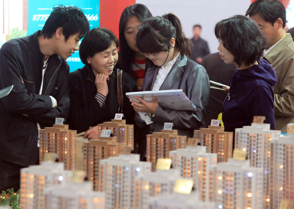 Potential homebuyers talk with a sales representative at a real estate fair in Tianjin, one of the cities affected by the latest round of tightened home loan policy. LIU DONGYUE / XINHUA