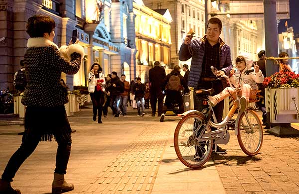 A girl poses for a photo while sitting in the basket of a bike owned by Mobike, a bike-sharing service provider, at the Bund in Shanghai on New Year's Eve.Gao Erqiang / China Daily