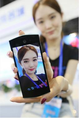 A staff member displays her selfie edited by the photo app Meitu at an international software expo in Beijing on May 27, 2015. (Photo provided to China Daily)