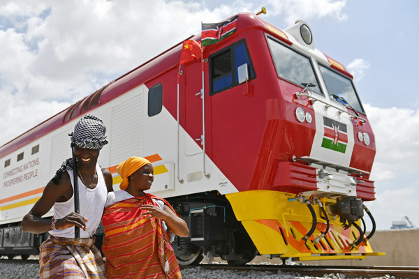 Locals stand beside a China-made locomotive at Port Reitz in Mombasa, Kenya. (Photo/Xinhua)
