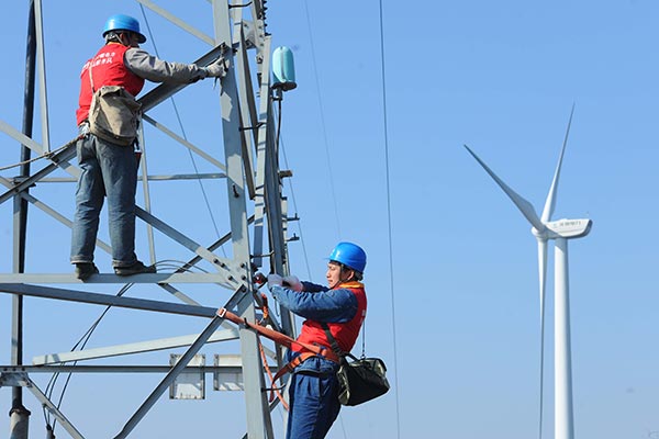 Workers with the power supply company in Chuzhou, Anhui province, check the transmission network under the State Grid before it is connected with a local wind power farm. (Photo/CHINA DAILY)