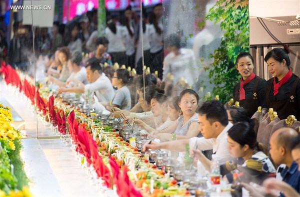 Diners eat around an extra large hotpot at the 8th China (Chongqing) Hotpot and Food Culture Festival in Southwest China's Chongqing, Oct 20, 2016. (Photo/Xinhua)
