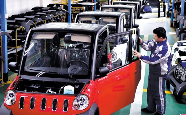 A worker checks a low-speed electric vehicle at a production line in Chuzhou, Anhui province. (Photo/CHINA DAILY)