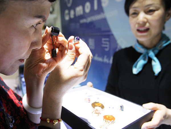 A buyer examines a sapphire at a Gemoiselle Jewelry store in Beijing. ZHANG WEI / CHINA DAILY
