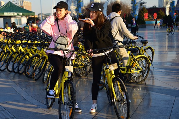 Two girls get ready to ride Ofo bicycles in Tianjin. (Photo/China Daily)