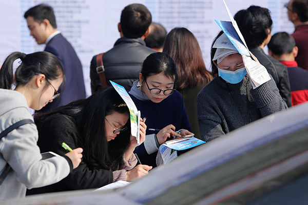 Job seekers check out information on companies at a career fair in Hangzhou, Zhejiang province. (Photo/China Daily)